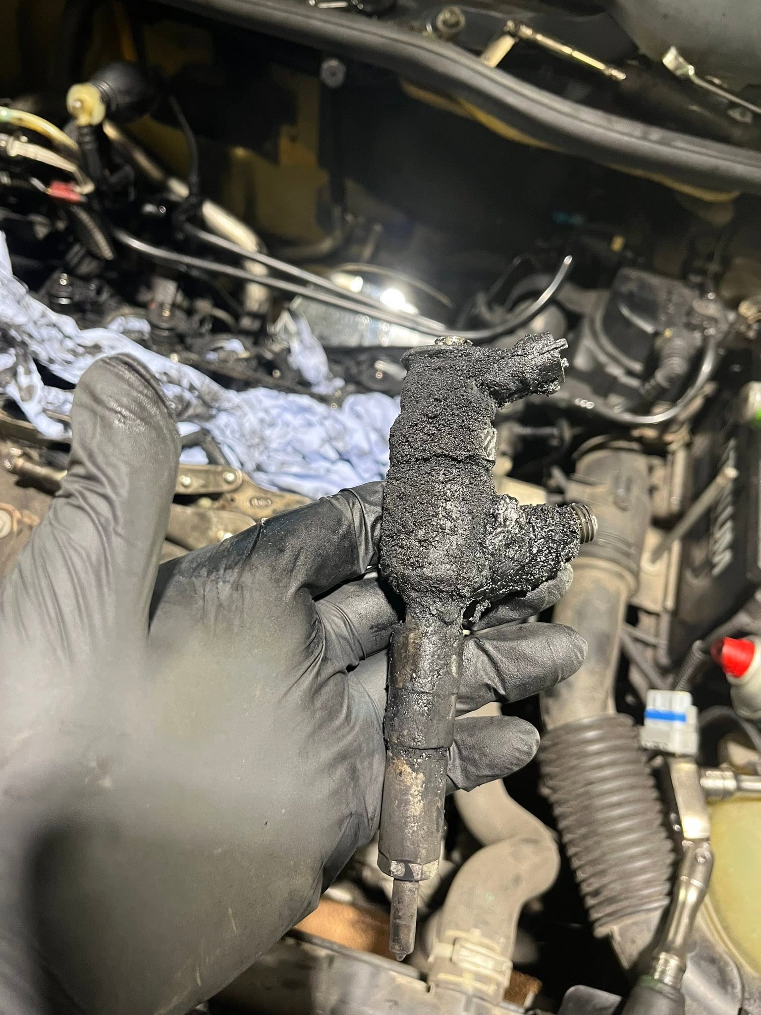 Heavily carbon-fouled diesel injector held up after removal from the engine