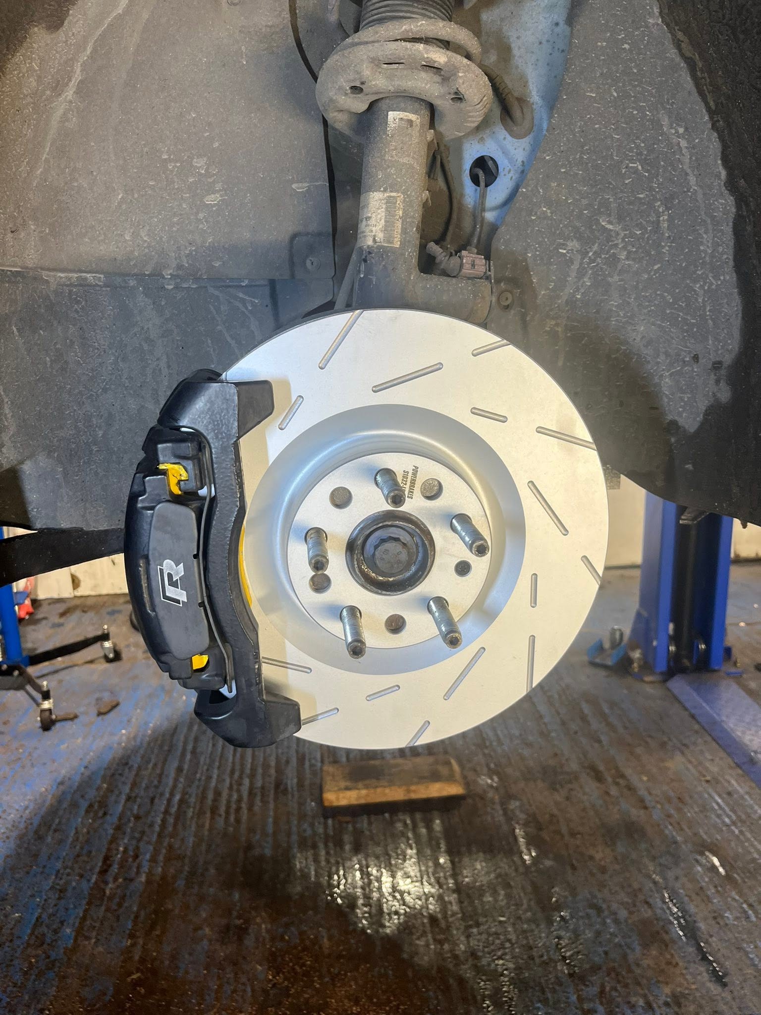 New slotted brake disc and caliper fitted to a car on the ramp