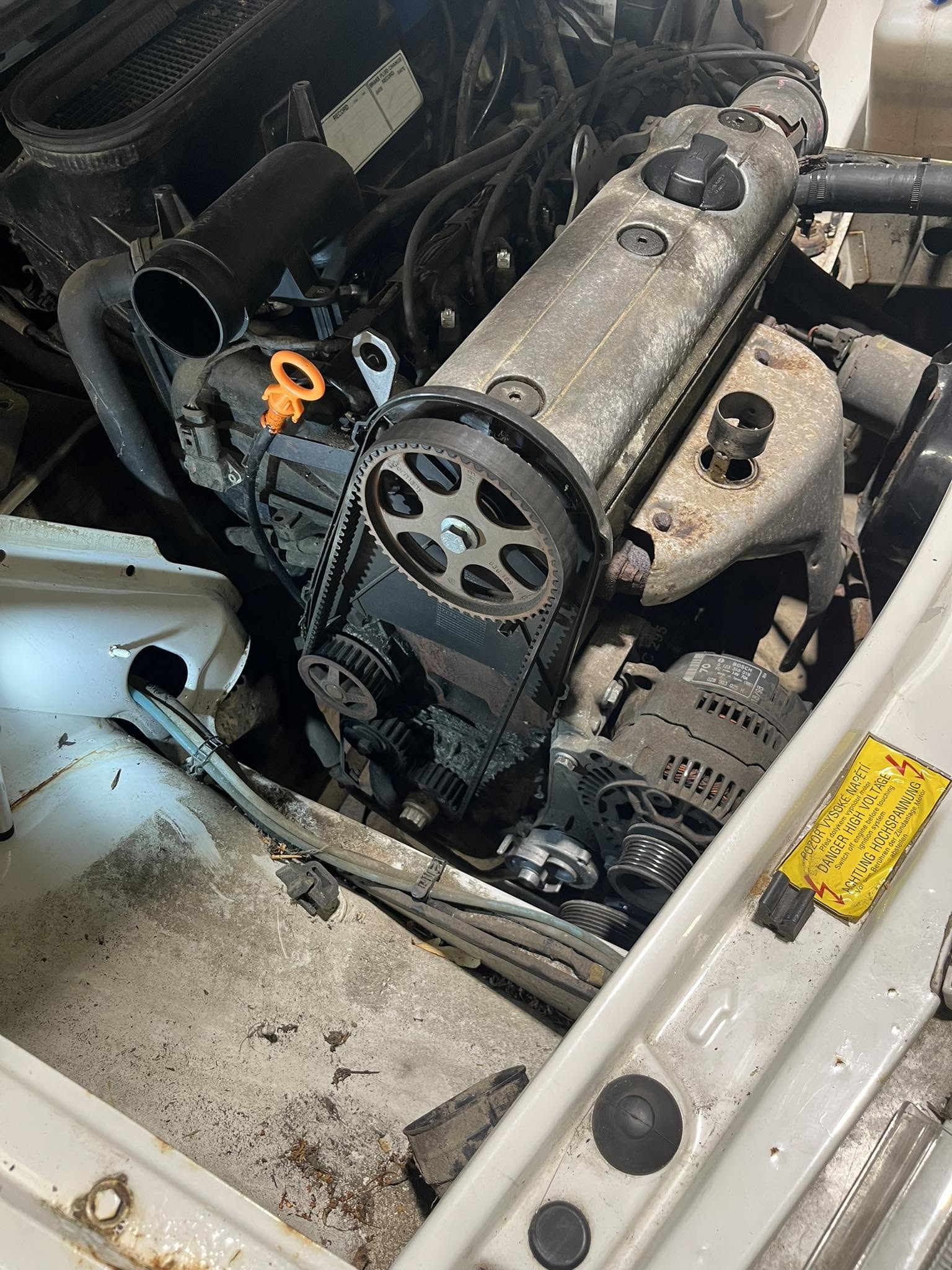 Engine bay with timing covers removed showing the camshaft pulley and belt
